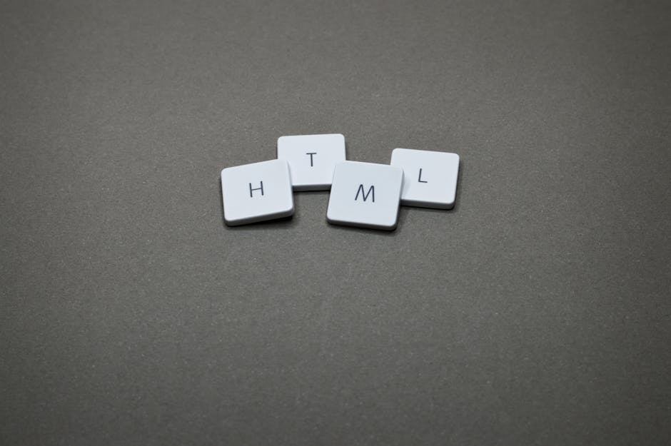 Four white letter tiles are arranged on a smooth, grey surface, with the letters H, T, M, and L visible. The tiles have a matte finish and are positioned in a loose cluster, with some slightly overlap
